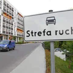 Znak "Strefa ruchu" na drodze wewnętrznej obok nowoczesnego osiedla.