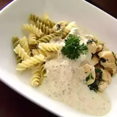 Pâtes fusilli, poulet et sauce crémeuse, garnies de persil. Un délice de pâtes pesto mozzarella.