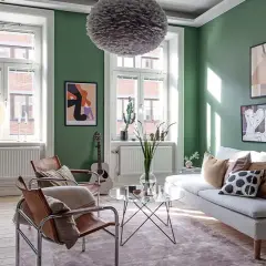 Salón verde con sofá blanco, sillones de cuero y arte abstracto. Ideas para **como ahorrar en calefacción** con estilo.