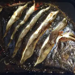 Rodaballo al horno, con cortes profundos que revelan su carne blanca y jugosa, listo para ser disfrutado.