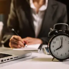 Budzik pokazuje 8:00, a osoba pisze w notatniku. Ile godzin pracy jeszcze przed nią?