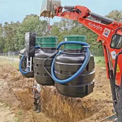 Koparka Kubota montuje zbiorniki oczyszczalni biologicznej. Czasem pojawia się pytanie, dlaczego śmierdzi z oczyszczalni biologicznej, ale tu widzimy proces instalacji.