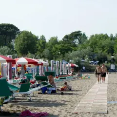 Plaża w Caorle, Santa Margherita. Rzędy parasoli i leżaków, ludzie odpoczywają. Idealne miejsce na camping.