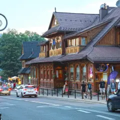 Spacer po tętniącym życiem białka tatrzańska centrum. Drewniane budynki, ruch uliczny i ludzie tworzą malowniczy widok.