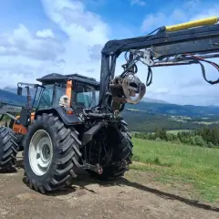 Ein gebrauchter Forstkran mit Greifer an einem Traktor, bereit für den Einsatz im Wald.