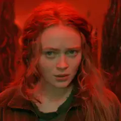 Max, le regard perdu dans le monde inversé de Stranger Things, entourée de formes sombres et menaçantes.