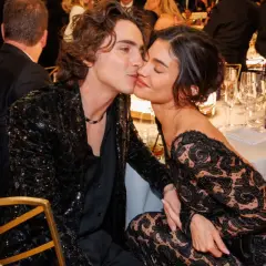 Kylie Jenner i Timothée Chalamet w czarnych, eleganckich strojach, podczas romantycznego momentu przy stole.