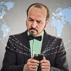 Mężczyzna zmartwiony patrzy na telefon, zastanawiając się, co to roaming i jak działa globalna sieć.