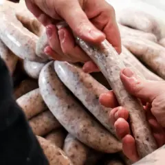 Dłonie formują białą kiełbasę, zastanawiając się, jakie przyprawy do białej kiełbasy nadadzą jej najlepszy smak.