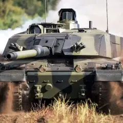 Challenger 2, potężny czołg, pędzi przez teren, wzbijając tumany kurzu i dymu.