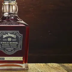Butelka Jack Daniel's Single Barrel Tennessee Whiskey, z bogatym, bursztynowym kolorem, stoi na drewnianym blacie.