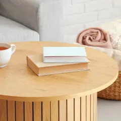 Kubek z herbatą i dwie książki na drewnianym stoliku. Idealne inspiracje, co postawić na stolik kawowy, by stworzyć przytulną atmosferę.