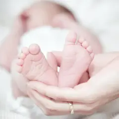 Manos sostienen los pies de un bebé, un sueño hecho realidad.