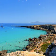 La spiaggia più bella di Favignana: acque cristalline, scogliere dorate e barche all'ancora. Un paradiso terrestre.