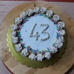 Torta di compleanno particolare con decorazioni a rosa e codette colorate, numero 43 in crema.