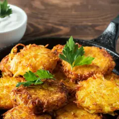 Goldbraune Kartoffelpuffer im Gusseisenpfännchen, perfekt für ein Kartoffelpuffer Rezept. Dazu ein Schälchen cremiger Dip.