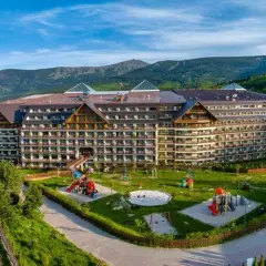 Duży hotel z placem zabaw i widokiem na góry.