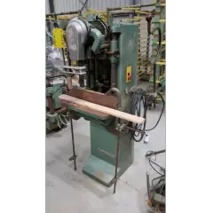 Machine à bois verte, une mortaiseuse à chaîne, avec une pièce de bois en position.