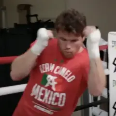 Boxer in a red "Team Canelo Mexico" shirt practices shadow boxing in a ring, his fists wrapped and ready.