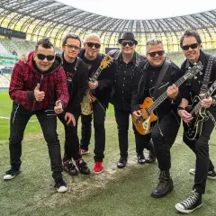 Zespół Big Cyc na murawie stadionu, gotowy do zagrania swoich największych hitów.