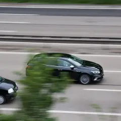 Czarny samochód wyprzedza inny pojazd na autostradzie.