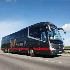 Czarny autokar Lux Express z napisem "Podlasie Express Białystok-Warszawa Okęcie" jedzie po autostradzie.