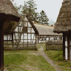 Skansen z chatami krytymi strzechą, drewnianymi płotkami i ścieżką. Idealne miejsce na odkrywanie kluki atrakcje.