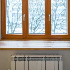 Neue Fensterbank aus Holz, auf die alte geklebt, mit Blick auf Bäume im Winter. Heizkörper darunter.