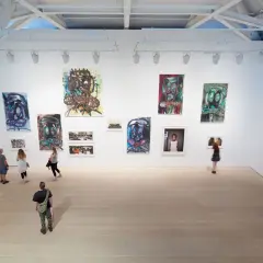 Visitors explore a vibrant exhibition, showcasing bold portraits and mixed media pieces that define the dynamic London art scene.