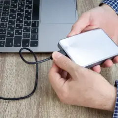Hände verbinden eine externe Festplatte mit einem Laptop. Plötzlich kein Zugriff auf externe Festplatte.