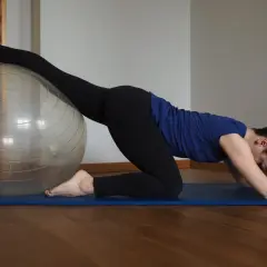Kobieta na macie ćwiczy z piłką, rozciągając nogę. Widać, co daje stretching: lepsza gibkość i relaks.
