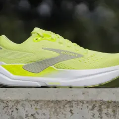 Jaskrawożółte buty Brooks Ghost Max, jedne z najdroższych butów do biegania, na betonowym murku.