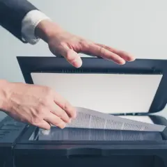 Un homme en costume utilise un scanner ged pour numériser un document important.