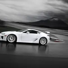 Biały Lexus LFA na torze wyścigowym, z rozmytym tłem gór i nieba.