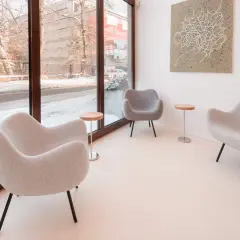 Nowoczesne fotele i stoliki tworzą przytulną przestrzeń, idealną do nauki podczas kursu fotografii wnętrz. Za oknem zimowy krajobraz.