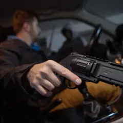 Mężczyzna w samochodzie trzyma pistolet na kule gumowe. Czy pistolet na kule gumowe jest legalny? To pytanie nurtuje wielu.