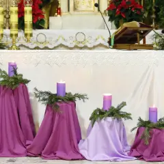 Fioletowe świece i gałązki jodły tworzą piękne dekoracje adwentowe w kościele.