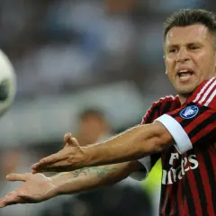 Piłkarz Cassano w koszulce Milanu, z wyrazem frustracji na twarzy, gestykuluje w stronę lecącej piłki.