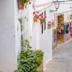 Calle estrecha en el centro de Almería, con casas blancas, flores y una tienda de ropa.