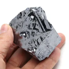 Ein Mensch hält ein Stück Silizium, dessen Oberfläche wie eine glänzende, metallische Haut mit komplexen Mustern aussieht.