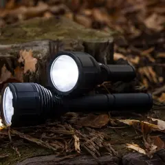 Dwa potężne latarki leżą na leśnym poszyciu. Czy 3000 lumenów to dużo? Zdecydowanie tak, rozświetlają jesienne liście i drewno.