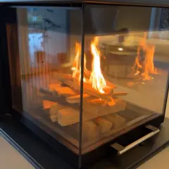Ein moderner Kamin mit brennendem Holz. Die Flammen tanzen und geben ein warmes Licht ab, das die Frage aufwirft, wie lange brennt ein holzscheit wohl?