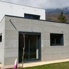 Extension moderne en parpaing gris, 20m2, avec grandes baies vitrées et vue sur montagnes. Estimation du prix extension 20m2 en parpaing.