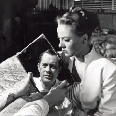 Kobieta trzyma lustro, w którym odbija się mężczyzna z blizną na twarzy. Klimat typowy dla **film noir**.