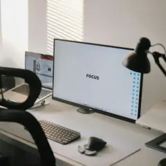 Ein aufgeräumter Schreibtisch mit dem Wort "FOCUS" auf dem Monitor, der eine "clean desk policy" verkörpert.