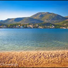 Słoneczna plaża i spokojne morze w Słano, Chorwacja. W oddali widać urokliwe **małe wyspy chorwackie** i zielone wzgórza.