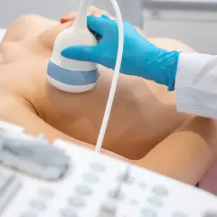 Badanie usg klatki piersiowej. Lekarz w niebieskiej rękawiczce wykonuje badanie ultrasonograficzne piersi pacjentki.