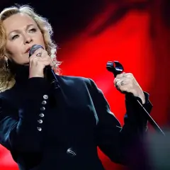 Artystka śpiewa z pasją, jakby mówiła "kocham cię życie tekst". Czerwone tło podkreśla jej emocje.