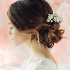 Delikatny kok boho z białymi kwiatami we włosach, idealny na ślub w plenerze.