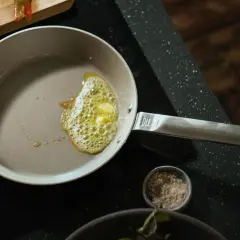Butter schmilzt in einer beschichteten Pfanne, bereit für das Braten von Fisch. Die Pfanne wird nach dem Kochen einfach zu reinigen sein.